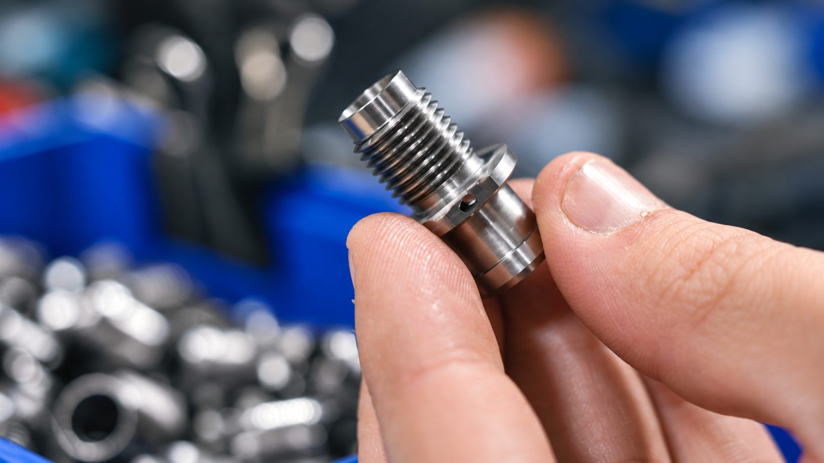 Hand holding a precision-machined metal component in a workshop