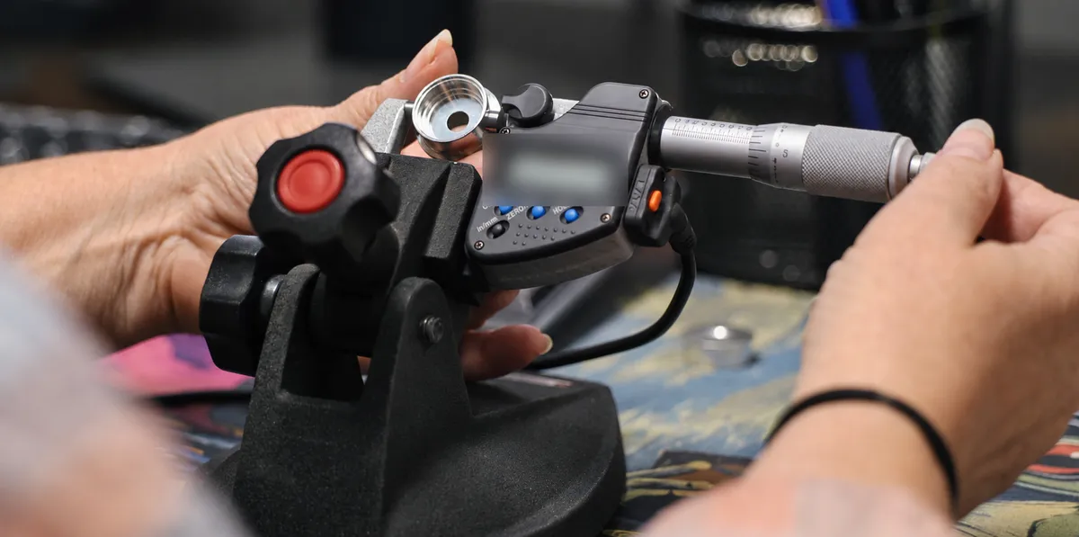 Inspector measuring a machined cup with a digital micrometer