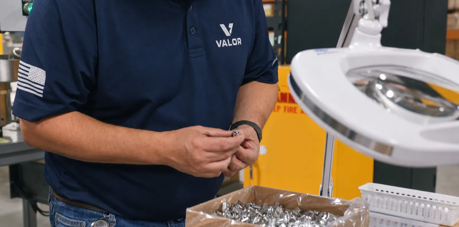 Valor Tactical technician inspecting a machined component under a magnifier lamp